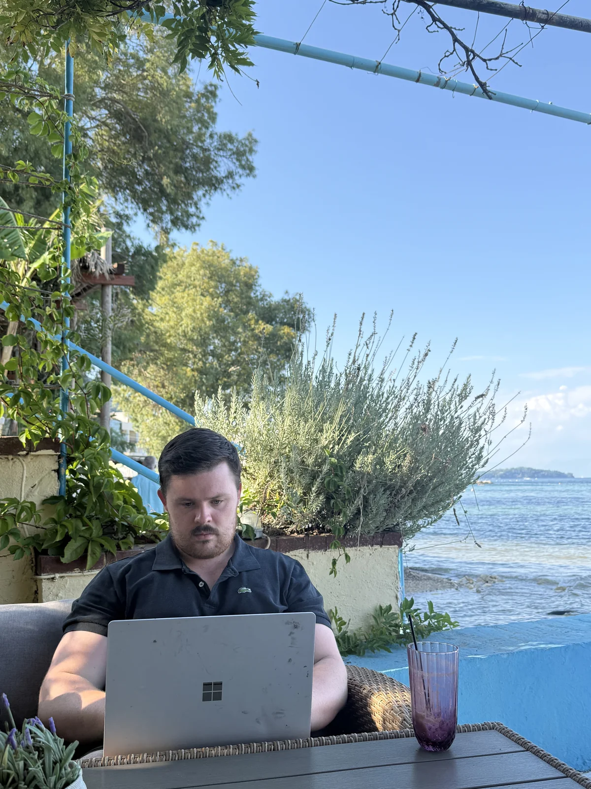Charlie Johns working on a laptop with a sea view